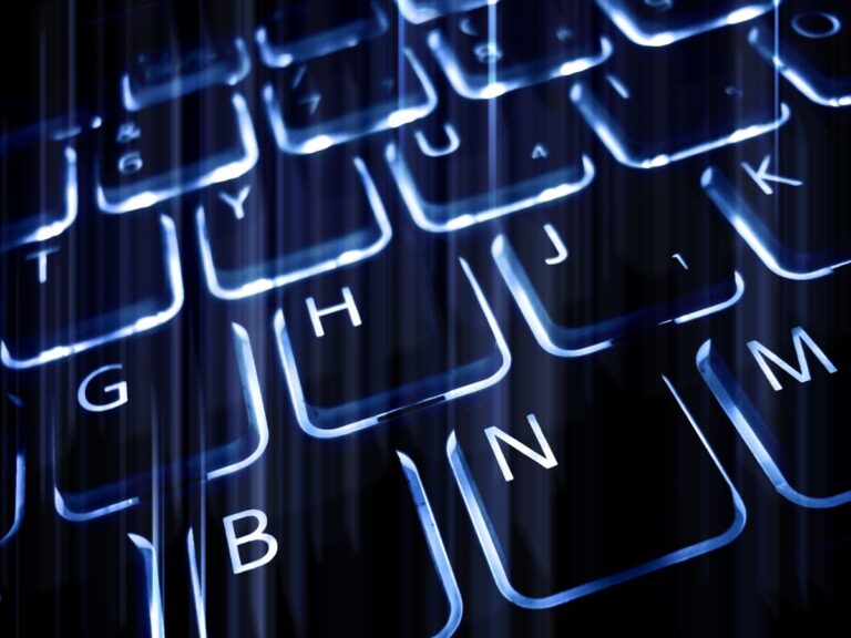 Close up of illuminated computer keyboard keys in blue light with vertical digital streak effects. The manipulated perspective emphasizes technology, data processing, and modern digital computing concepts.