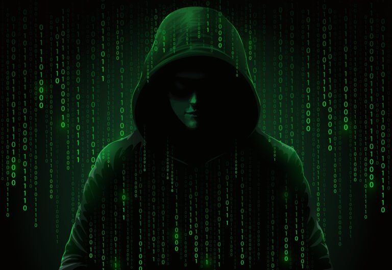 Silhouetted figure in a hoodie with face partially obscured, surrounded by cascading green binary code on a dark background. The image represents a computer hacker and cybersecurity threats such as data theft and cyberattacks on digital infrastructure.