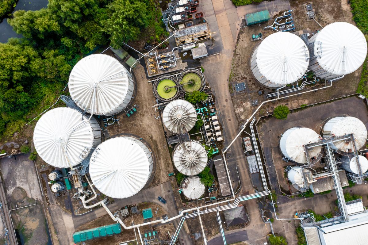 Aerial view directly above storage tanks and silos with connecti Aerial view of large industrial tanks and pipes in an industrial facility, surrounded by greenery.
