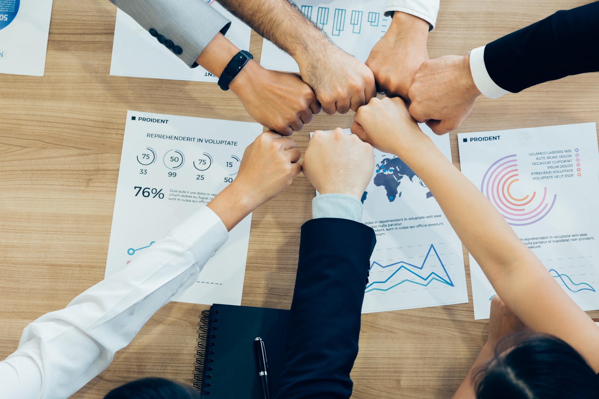 colleagues-stacking-hands-above-table-with-papers.jpg - Certrec