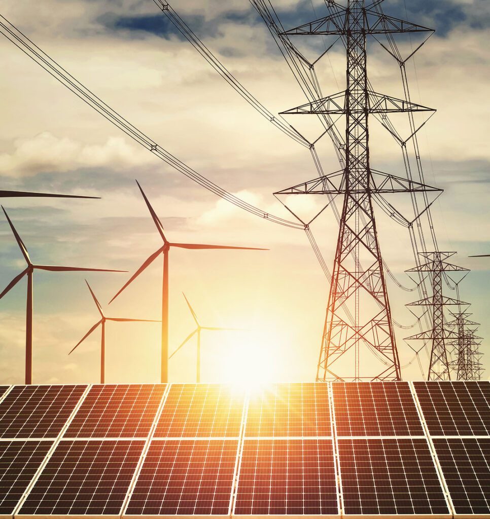 High voltage transmission towers and power lines stretching across the horizon with wind turbines turning at sunset. The image represents NERC registration and compliance support for electric grid infrastructure and renewable energy assets.