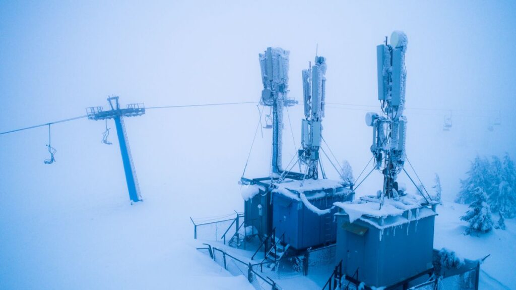 Snow covered power plant with ice coated cell towers during a severe winter storm. Deep snow and heavy frost surround the facility, showing the impact of extreme cold on energy infrastructure.