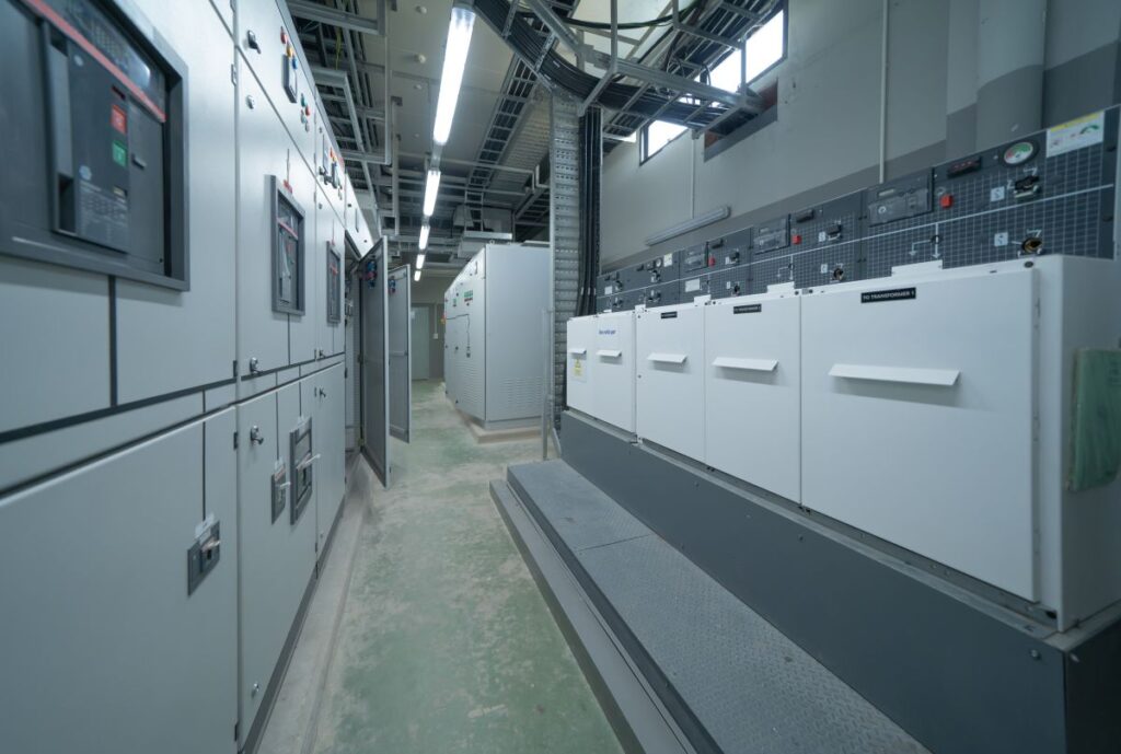 Interior of an electrical room with power energy machinery cabinets and transformers in a factory setting.