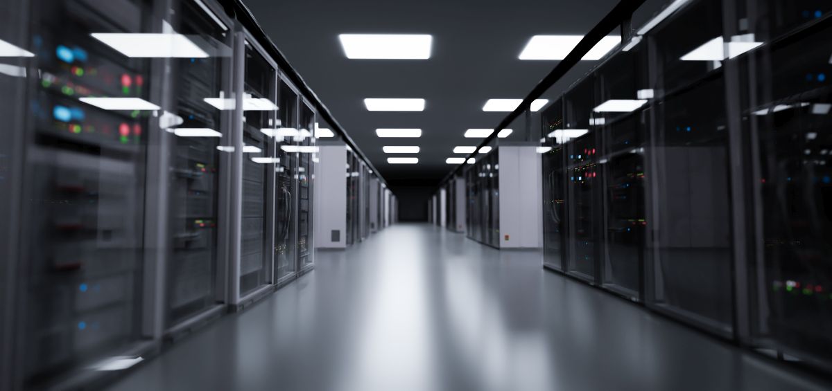 Modern data center server room with glass rack cabinets lining a long brightly lit hallway.