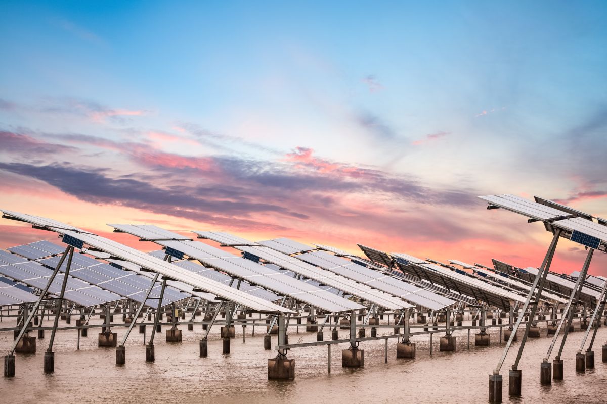 Rows of solar panels at a solar farm reflecting the sky at dusk.