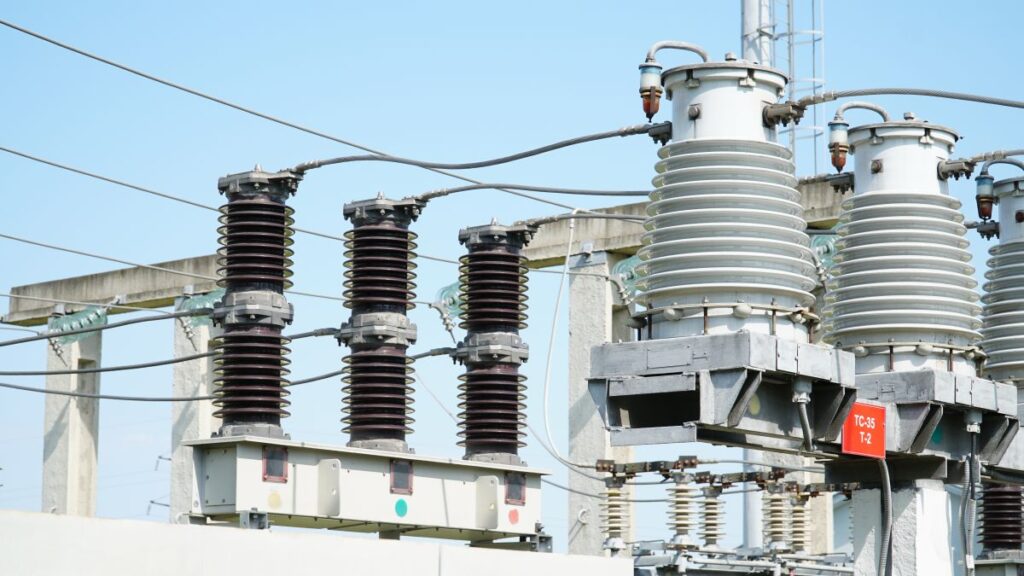 The image shows high and low voltage transformer bushings with electrical insulation at a power substation.