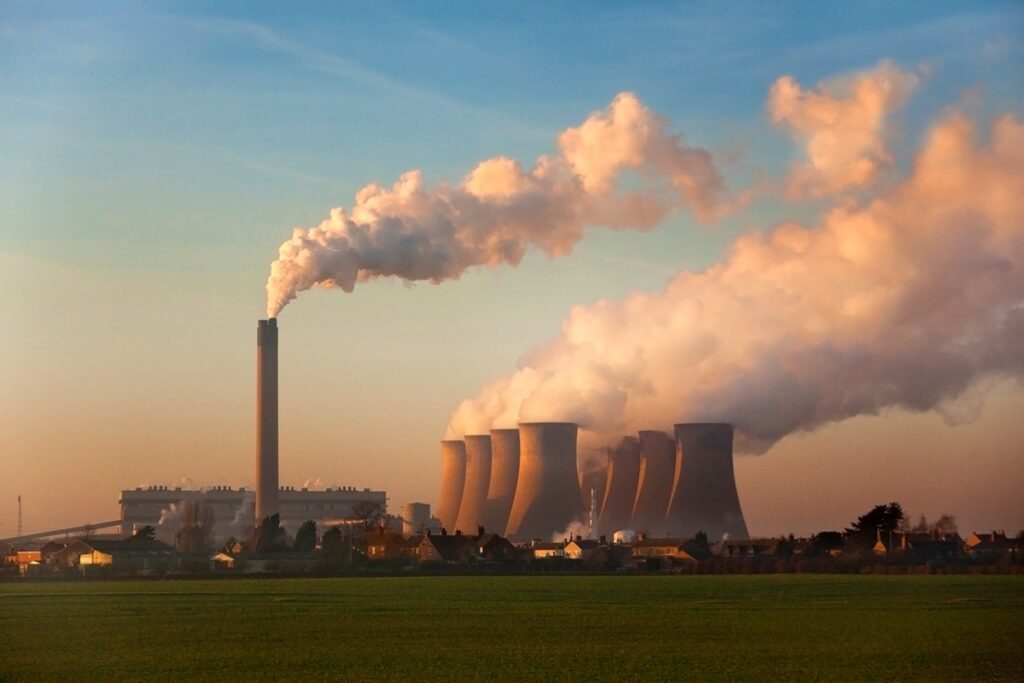 Power plant with smoke stacks and cooling towers, representing the profitability of natural gas and coal power plants.