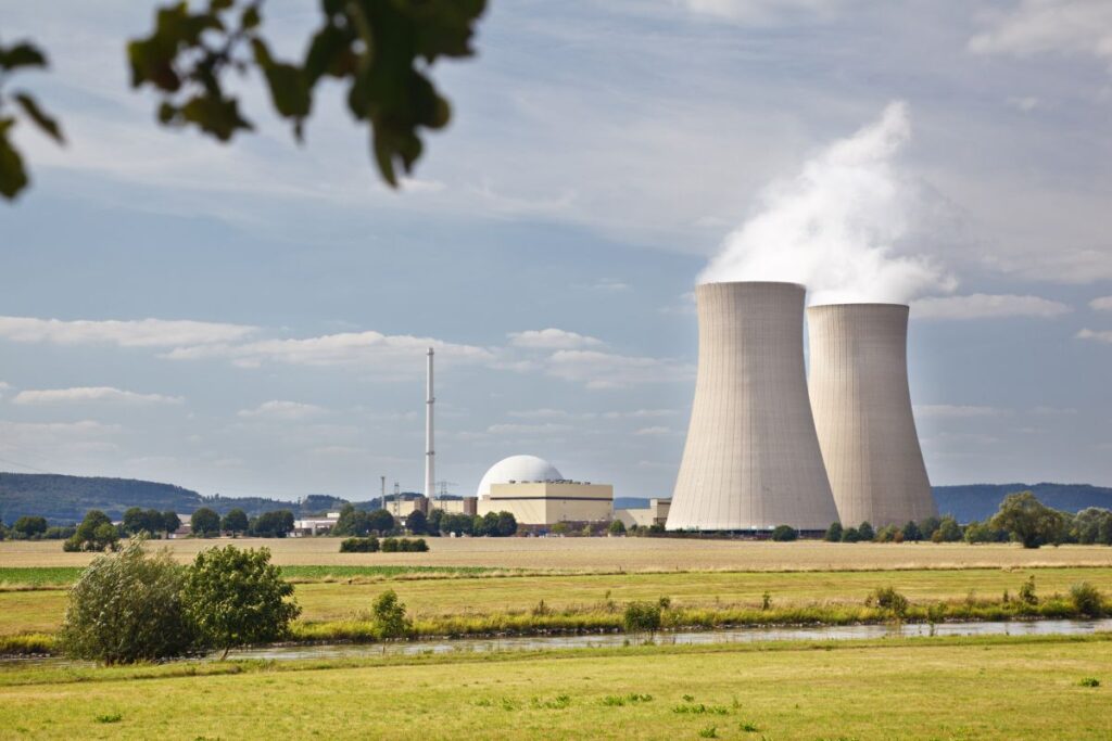 Nuclear power plant with cooling towers releasing steam across a rural landscape, representing key U.S. nuclear microreactors.