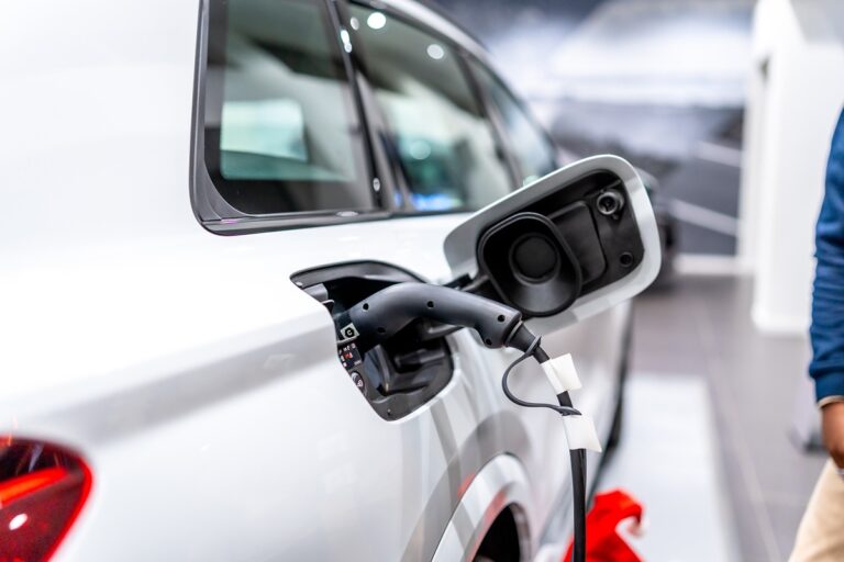 Hybrid Sales Rise While Battery Electric Sales Remain Lower After Tax Credit Expiration-Certrec Close-up of a white electric car charging port with a plugged-in charging cable.