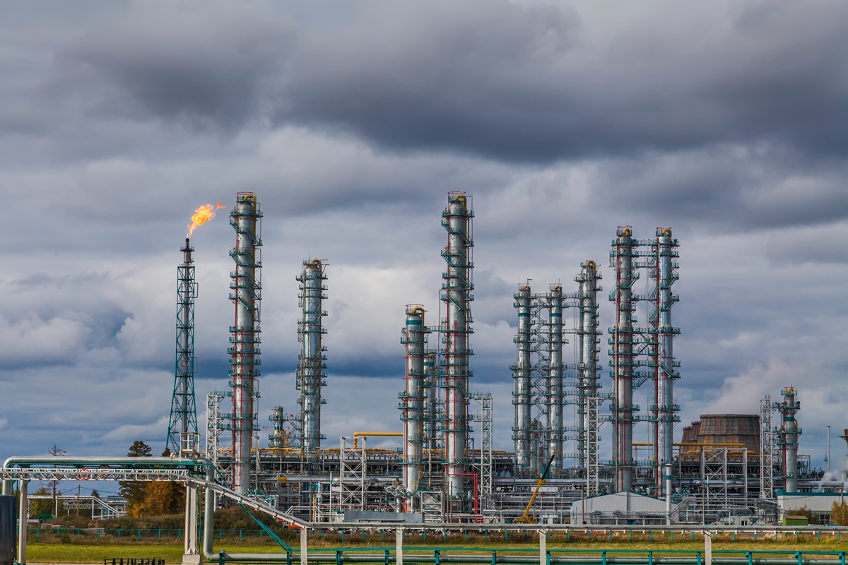 PJM Opposes Waiver for B Gas-Fired Plant in Fast-Track Interconnection Review-Certrec Oil refinery with tall processing towers and a flame at the flare stack against a cloudy sky