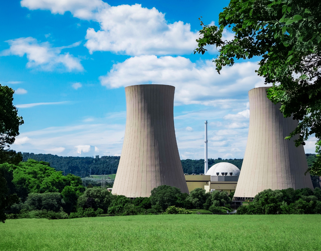 nuclear_earthday_cropped Two massive concrete cooling towers stand among green trees on a sunny day at a power plant. a white dome-shaped building and a tall chimney are visible between the towers.